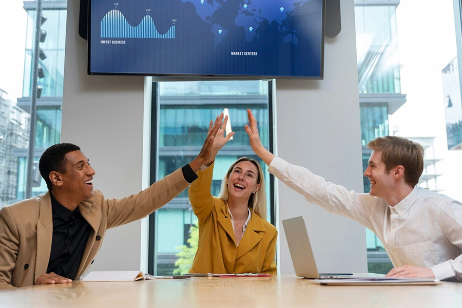 Vectradigi team celebrating sucess in the office with display screen in the background.