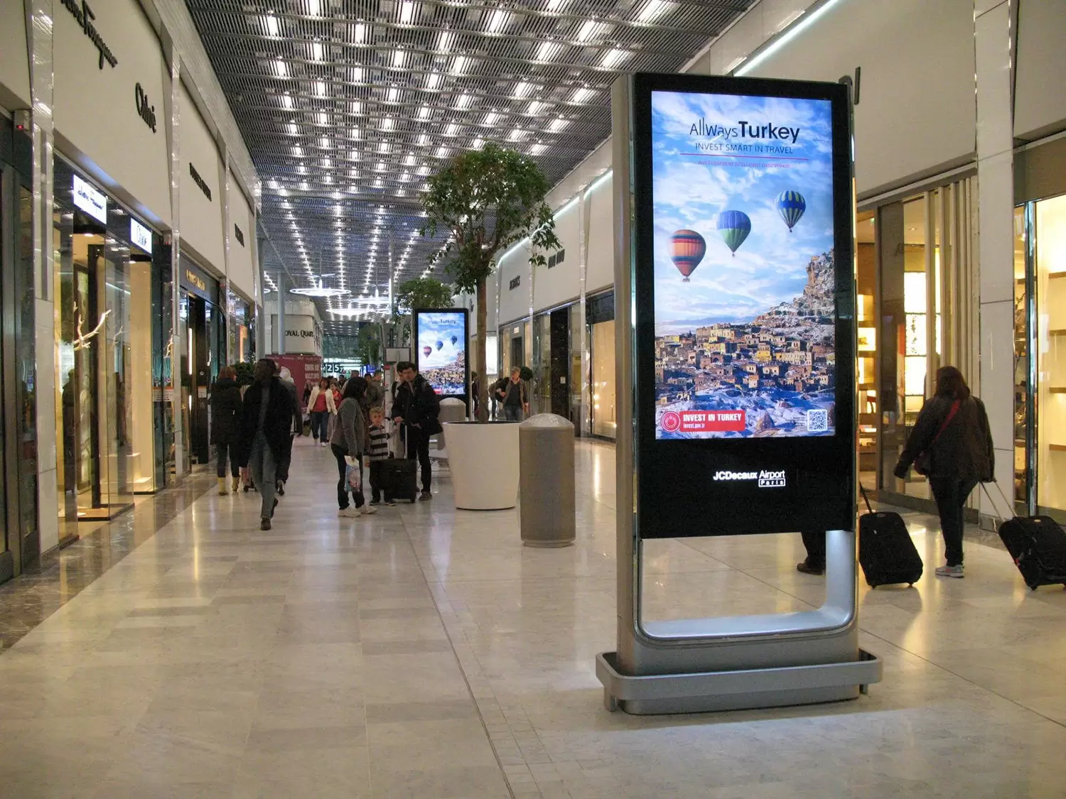 Indoor digital standee display in shopping mall showing promotional content.